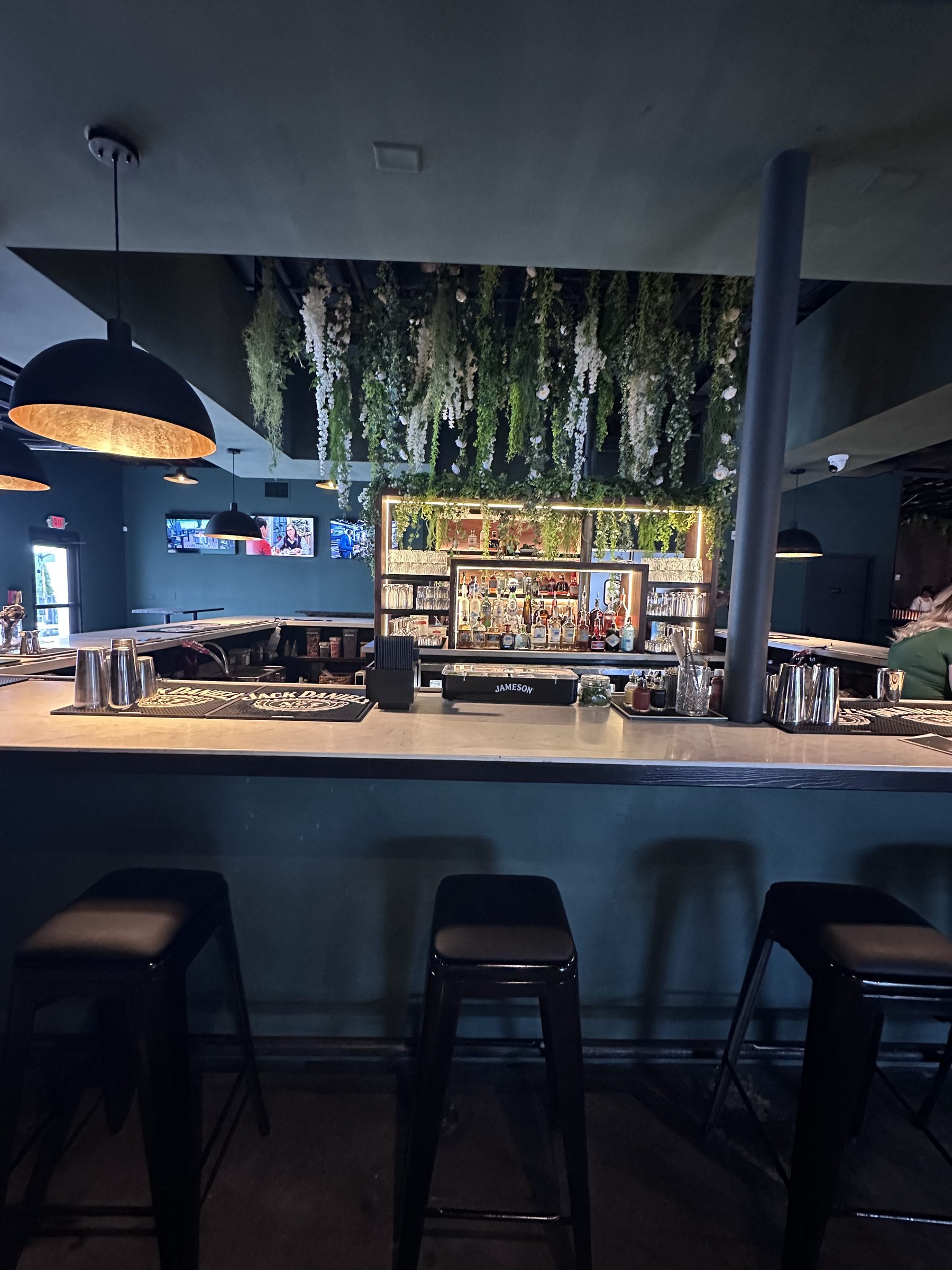 Bar with trailing greenery installation over backlit shelving