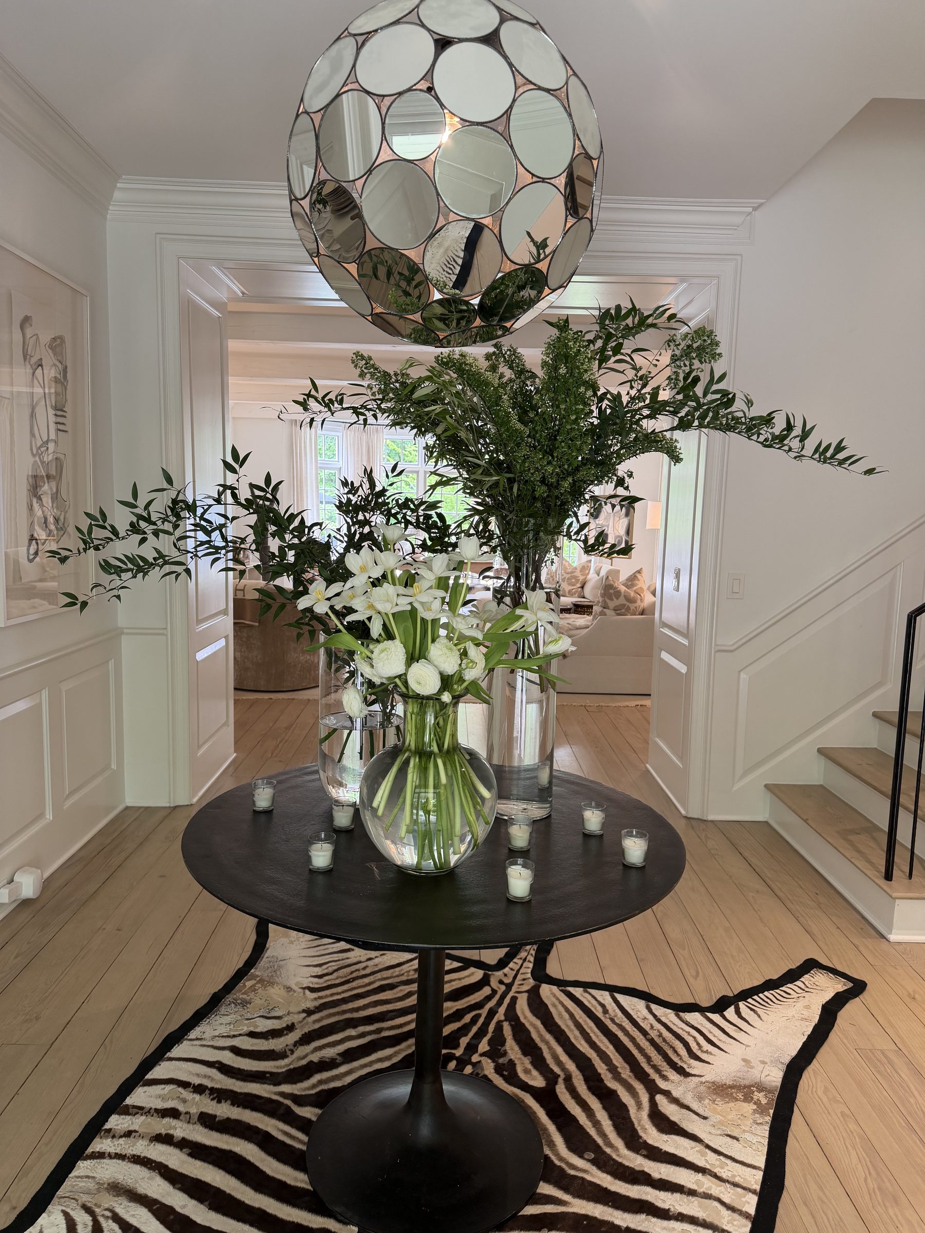 Entry foyer with round iron table, white florals and zebra hide rug