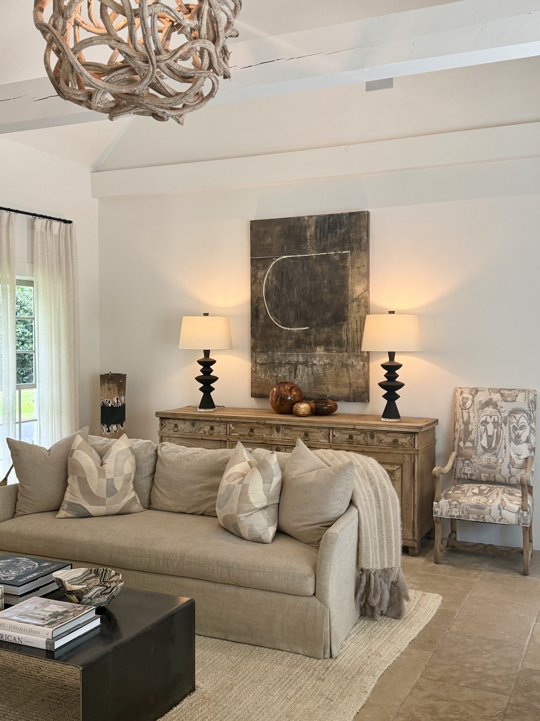 Living room with sculptural vine chandelier, linen sofa and antique oak sideboard