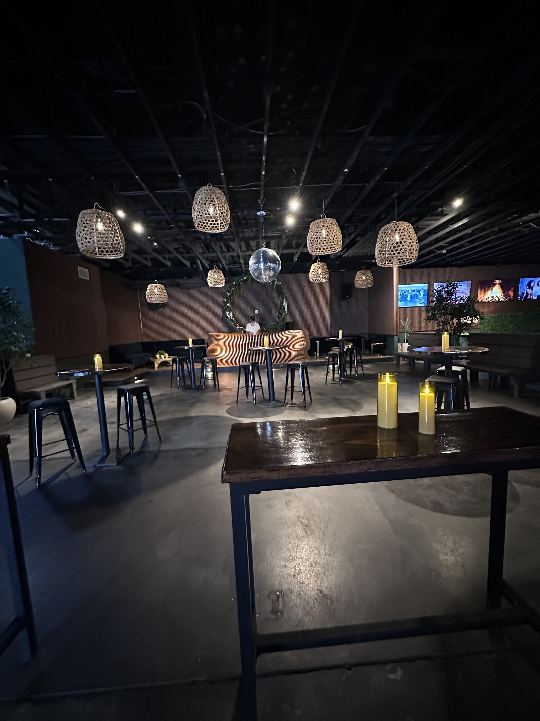 Moody lounge with woven pendants, disco ball and candlelit tables