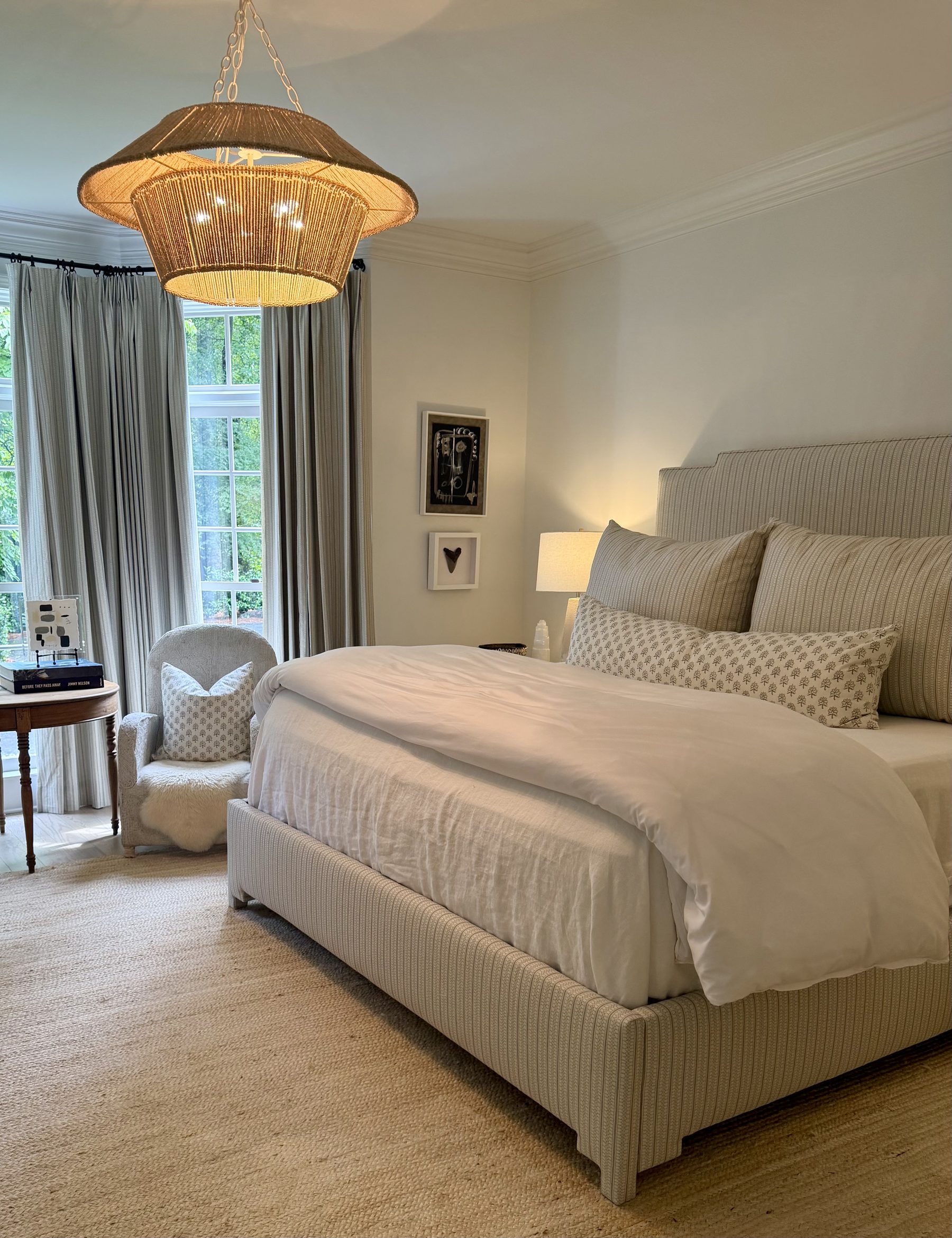 Primary bedroom with striped upholstered bed, jute chandelier and block print pillows