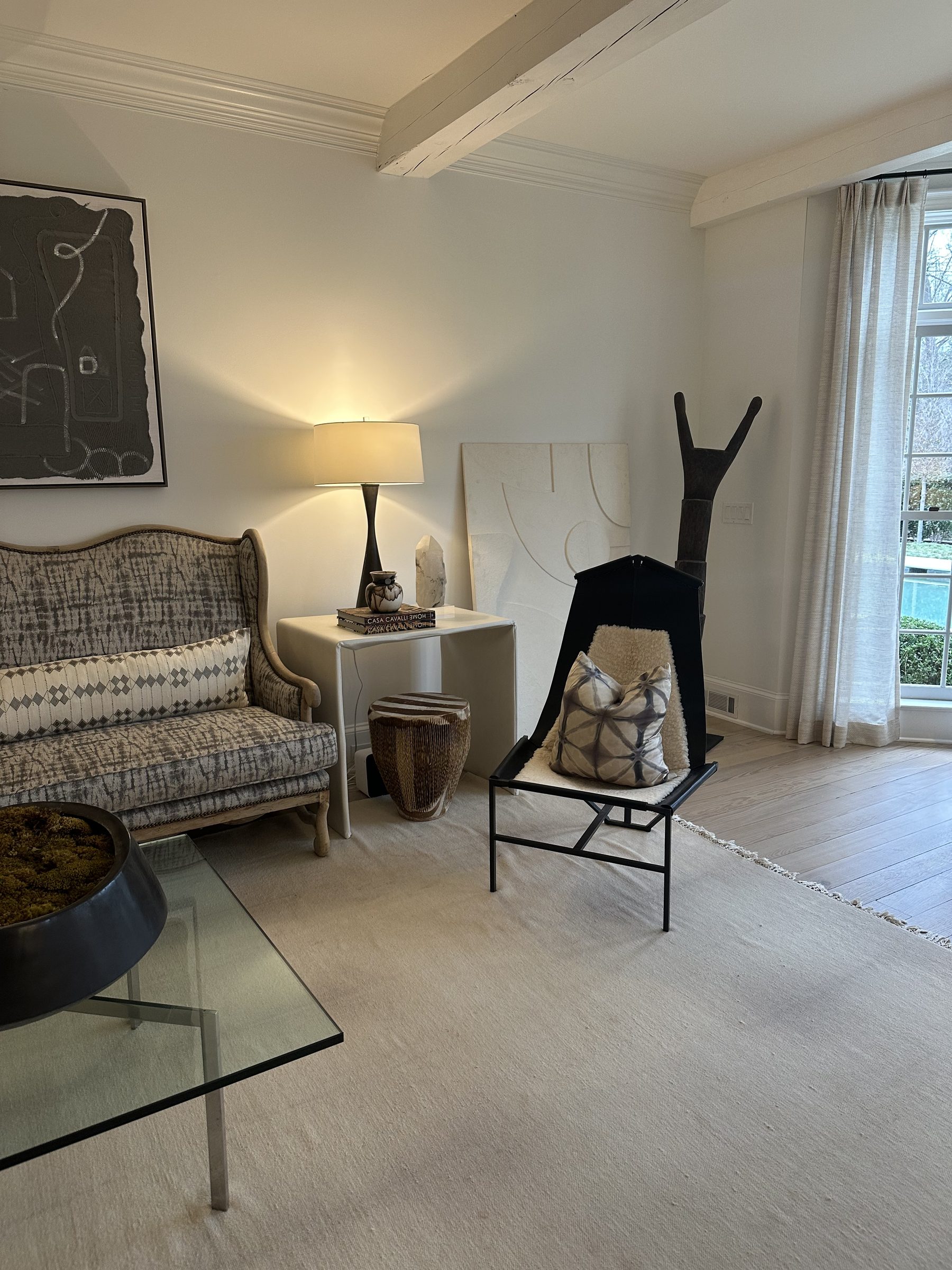 Sitting room with patterned settee, sculptural chair and collected art